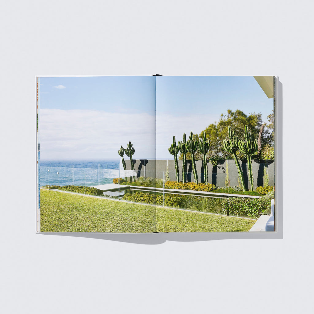 Open book showing a scenic view of trees and ocean on a white background